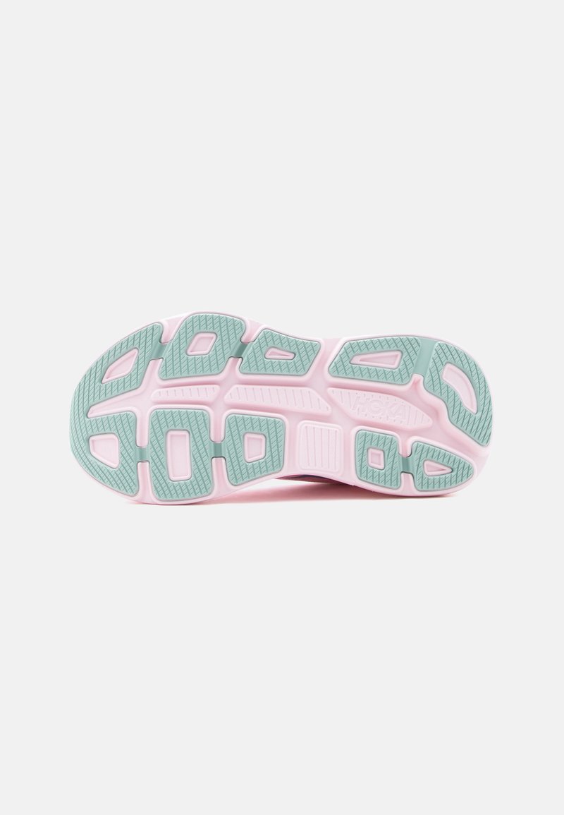 Semelle de chaussure avec base rose et coussinets en caoutchouc verts, montrant le motif de la bande de roulement et les rainures de flexibilité sur un fond blanc.