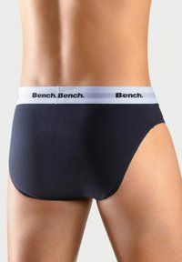 Schwarze Baumwollslips mit weißem elastischem Bund, der das wiederholte "Bench."-Logo zeigt. Glatte Textur, enganliegendes Design und hochgeschnittene Form.