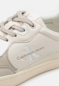 Sneakers Calvin Klein Jeans in pelle beige e crema, con texture lisce e scamosciate, dettagli con logo e lacci beige.