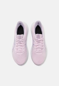 Un par de zapatillas deportivas de color rosa claro con suelas y cordones blancos, vistas desde arriba sobre un fondo blanco liso.