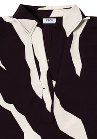 Camicia con colletto di un viola scuro con un sorprendente motivo astratto bianco, dotata di pattina e una superficie liscia, l'etichetta legge "CECIL."