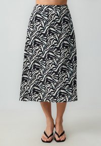 Maxirock aus einem gemusterten Stoff mit schwarz-weißen botanischen Designs und tealfarbenen Akzenten, versehen mit einem flachen Bund.