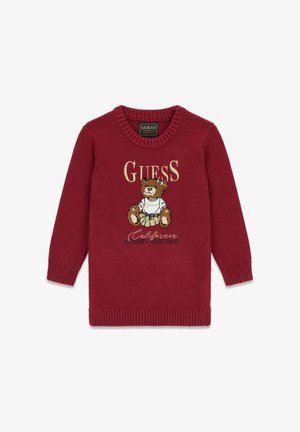 Pull en tricot rouge avec col et poignets côtelés, mettant en scène un ours en peluche portant une jupe et un pull, avec le texte "GUESS California Authentic Denim Brand".