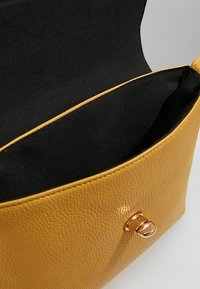 Borsa in pelle gialla a ciottoli con interno liscio, dotata di chiusura in metallo dorato e un unico scomparto.