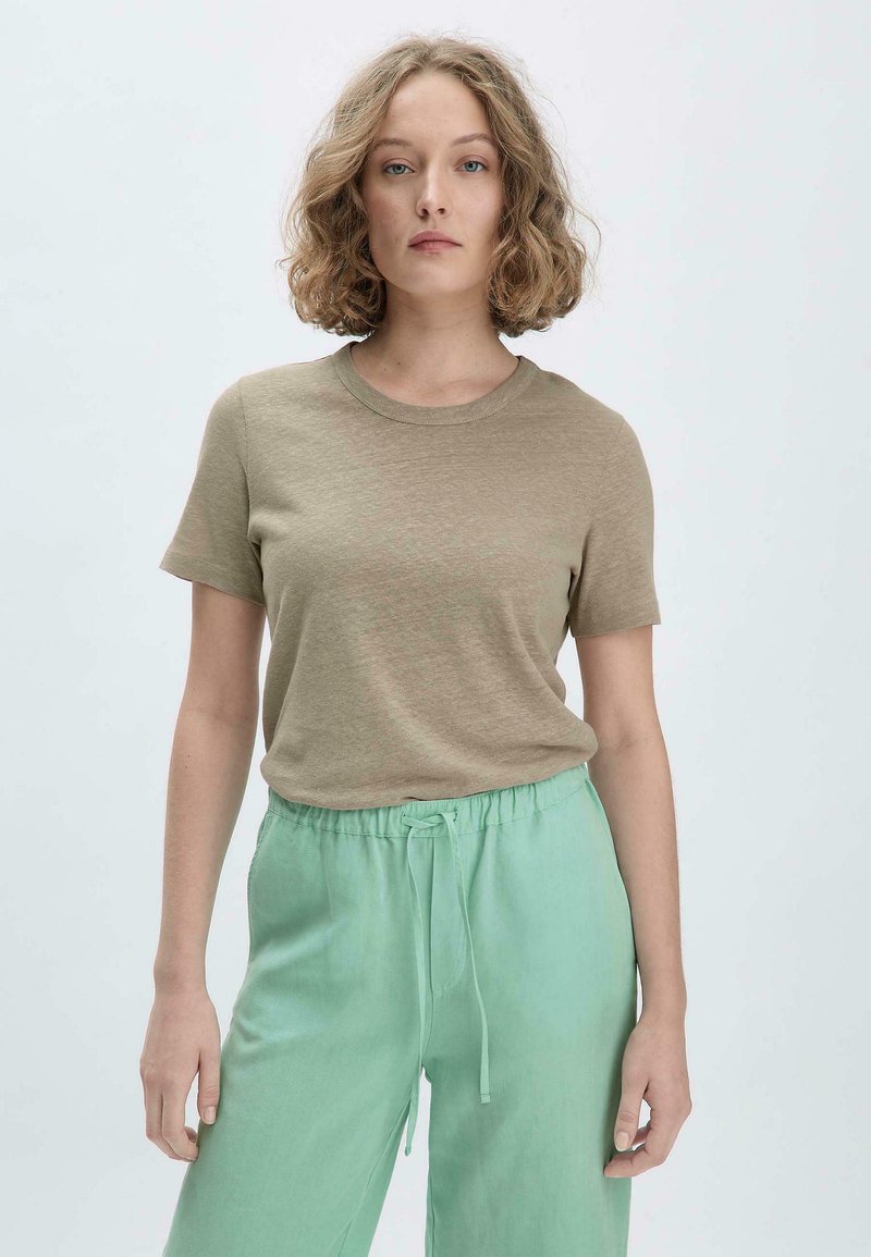 Hellbraunes, kurzärmliges T-Shirt aus weichem Baumwollstoff. Kombiniert mit lockeren, mintgrünen Hosen mit elastischem Bund und Kordelzug.