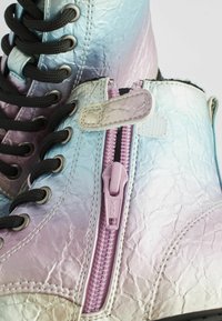 Bottes montantes iridescentes avec lacets noirs, surface texturée et une fermeture éclair latérale visible de couleur lavande. Présente des coutures contrastantes et des accents.