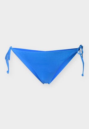 Slip bikini blu con lacci laterali, disposti in piano su uno sfondo bianco.