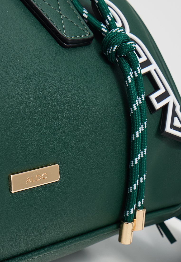 Borsa verde in similpelle con cordino intrecciato e dettagli bianchi, una placca con logo dorato e un dettaglio a trama cucita.