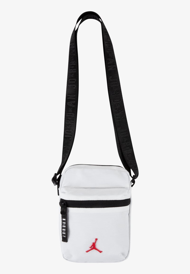 White crossbody bag with black strap, featuring a front zip pocket and red Jordan logo. Material appears durable with smooth texture.