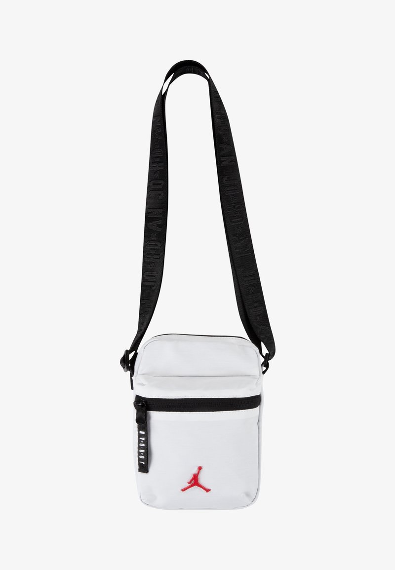 Bolsa crossbody branca com alça preta, apresentando um bolso frontal com fecho e o logótipo vermelho da Jordan. O material parece ser durável com uma textura suave.