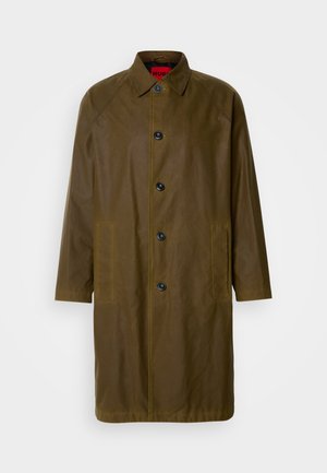 Olive rohelise veekindel ülerõivas sirge lõikega, nööpidega kinnitamine, küljetaskud ja kraega kaelus. Omab sujuvat tekstuuri.