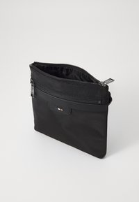 Sort nylon lynlomme med tekstureret overflade, der har en frontlomme og diskrete brandingdetaljer. Kompakt design til opbevaring af nødvendigheder.