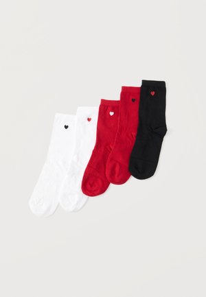 Cinq paires de chaussettes en blanc, rouge et noir, chacune ornée d'un petit cœur contrastant près du haut du bord-côte, disposées sur un fond clair.