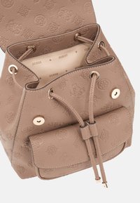 Bolso de cubo de cuero marrón claro con patrón de logo embosado, cierre de ajuste, herrajes en tono dorado y un bolsillo con tapa en la parte delantera. El interior presenta un forro con el logo de la marca.