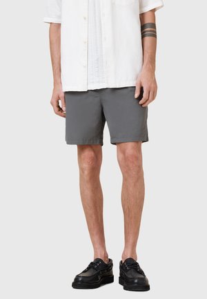 Grijze katoenen shorts met een eenvoudig ontwerp, midden dij lengte, en zijzakken, gecombineerd met zwarte veterschoenen en een witte overhemden.