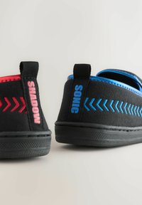 Black sneakers with red "SHADOW" and blue "SONIC" text on heel tabs, featuring matching colored chevron designs on sides.