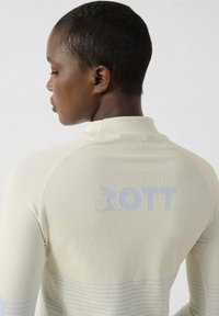 Maglietta sportiva a manica lunga color crema chiaro, con trama a costine, strisce orizzontali azzurro chiaro a contrasto e un logo discreto sul retro.