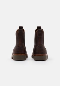 Καφέ δερμάτινες μποτες μέχρι τον αστράγαλο με ελαστικές πλευρικές επικαλύψεις και θηλιές. Διαθέτουν υφή, παχιά σόλα και επωνυμία στο πίσω μέρος.