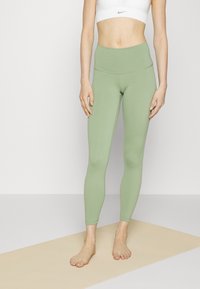 Jasnozielone legginsy z wysokim stanem, wykonane z elastycznego materiału, charakteryzujące się gładką fakturą i długością do kostek, bez widocznych wzorów.