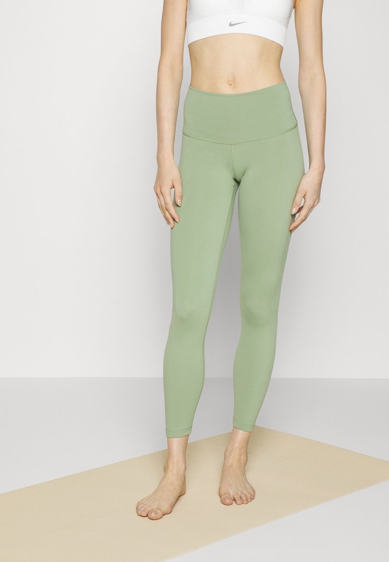 Jasnozielone legginsy z wysokim stanem, wykonane z elastycznego materiału, charakteryzujące się gładką fakturą i długością do kostek, bez widocznych wzorów.