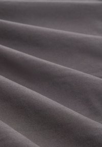 Tessuto grigio con una consistenza morbida e liscia, che presenta onde e pieghe delicate e distinte che creano profondità e dimensione.