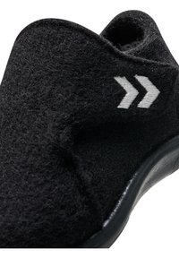 Svart filttoffel med en texturerad yta, böjd form och formgjuten sula. Har vita chevrondetaljer på sidan för att ge karaktär.