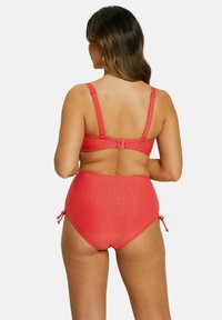 Bikini taille haute en corail vif avec une texture scintillante. Bretelles ajustables et liens sur les côtés pour un ajustement personnalisable.