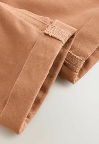 Cotton fabric in warm brown hue, featuring a simple design with folded hem and subtle stitching details, showcasing softness and texture.