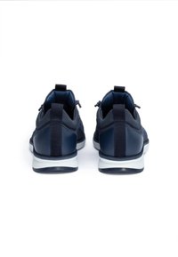 Un paio di sneakers blu navy con suole bianche, viste da dietro su uno sfondo bianco.