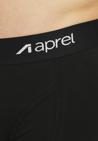 Schwarze, enganliegende Unterwäsche mit einer glatten Textur, ausgestattet mit einem breiten, elastischen Bund, auf dem der Markenname "aprel" in weißer Schrift zu sehen ist.