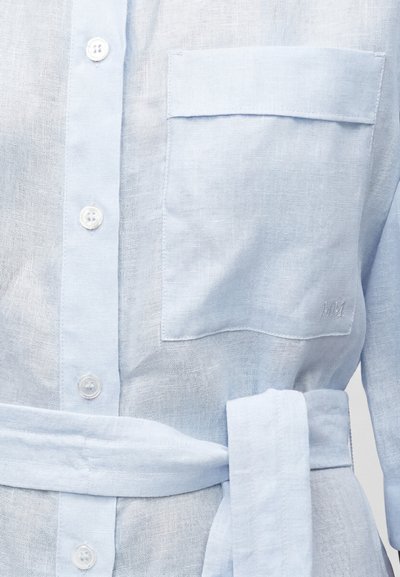 Φόρεμα πουκάμισο ανοιχτού γαλάζιου λινό με κουμπιά στο μπροστινό μέρος, τσέπη στήθους με καπάκι και υφασμάτινη ζώνη δεμένη γύρω από τη μέση.