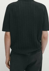 Polo shirt nera a maniche corte in maglia con un motivo testurizzato, caratterizzata da colletto a coste e orlo dritto.