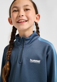 Hummel Performance zip-up sweatshirt in marineblauw met lichtblauwe accenten. Voorzien van een hoge kraag en een rits aan de voorkant, gemaakt van zachte, gestructureerde stof.