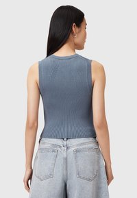 Blaues geripptes ärmelloses Oberteil mit rundem Ausschnitt, das an den Schultern feine Texturdetails aufweist und tailliert geschnitten ist. Wird mit hochgeschnittenen Jeans getragen.