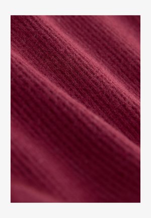 Bordeaux stof med et tekstureret, ribbet mønster. Overfladen virker blød og let fuzzy, og viser subtile variationer i nuancer.