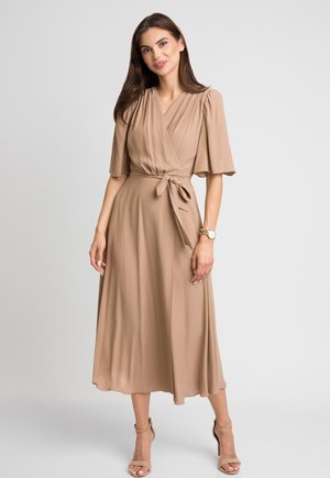 Brązowa sukienka o kopertowym kroju z krótkimi, rozkloszowanymi rękawami, wiązaniem w talii i zwiewnym dołem sięgającym do połowy łydki. Gładka faktura materiału.