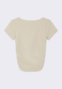 Haut beige à manches courtes avec une coupe décontractée, présentant une texture côtelée et des détails froncés sur les côtés, adapté à une tenue décontractée.