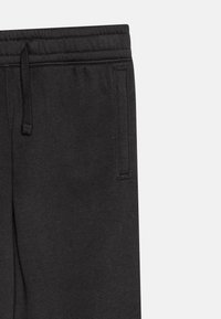 Schwarze Jogginghose aus weichem Stoff mit strukturierter Oberfläche, ausgestattet mit einem elastischen Bund mit Kordelzug und seitlichen Taschen.