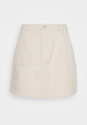 Beżowa spódnica dżinsowa o dopasowanym kroju, z bocznymi kieszeniami i kontrastowymi przeszyciami. Materiał ma gładką teksturę i czyste wykończenie.