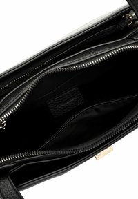 Borsa in pelle nera con superficie texturizzata, zip e ampio interno. Presenta una fodera liscia e una piccola etichetta all'interno.