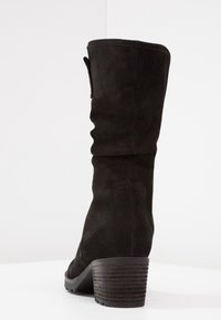 Bota de ante negra hasta la rodilla con un diseño arrugado y un tacón apilado. Presenta un acabado texturizado y detalles de costura visibles.