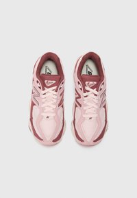 Des chaussures de sport roses et bordeaux en matériaux en maille et en daim. Elles présentent un design à lacets, un col rembourré et des accents de logo.