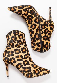 Ankle boots s leopardím vzorem, špičatou špičkou, vysokým stiletto podpatkem a bočním zipem. Vyrobeny z texturovaného materiálu s výraznými černými a oranžovými skvrnami.