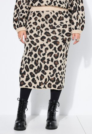 Strikket nederdel med leopardprint kombineret med matchende leopardprint trøje og sorte snørebånds militærstøvler på en person.