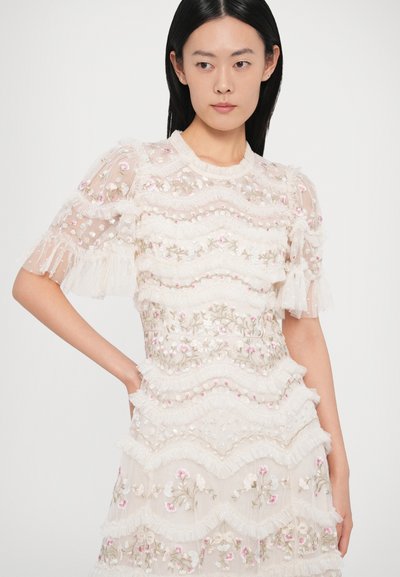 Vyšívané krátke šaty s krátkym rukávom z priehľadnej slonovinovej látky, ktoré majú vlnité vrstvy, kvetinové vzory a všade rozstrapkané detaily.