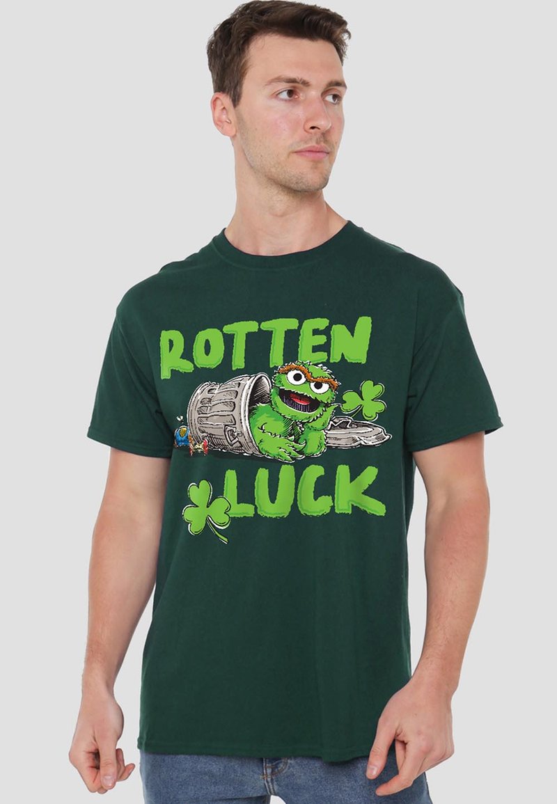 Green cotton t-shirt featuring a cartoon character emerging from a trash can, with "ROTTEN LUCK" in bold green letters and a clover symbol.