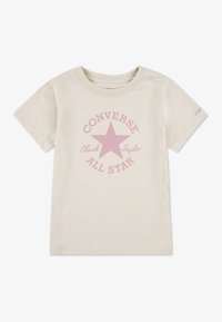 Světlé béžové bavlněné tričko s růžovou hvězdou a kruhovým nápisem "CONVERSE" a "Chuck Taylor". Krátké rukávy, kulatý výstřih.