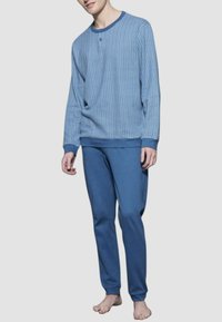 Pullover blu lavorato a maglia con motivo a spina di pesce e scollo a girocollo, abbinato a pantaloni blu solidi. Entrambi gli articoli hanno una vestibilità comoda.