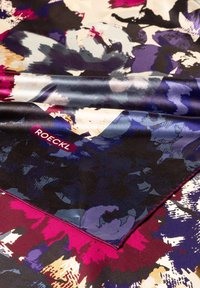 Silk square scarf featuring an abstract floral pattern in vibrant colors, with a deep purple, pink, and black design, and a label reading "ROECKL."