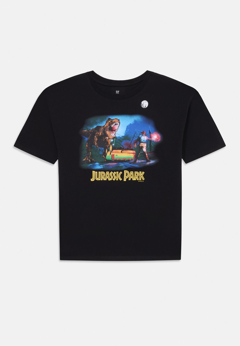 T-shirt noir à manches courtes présentant un graphique coloré de Jurassic Park avec un dinosaure, un explorateur et un véhicule, le tout sur fond de ciel nocturne.